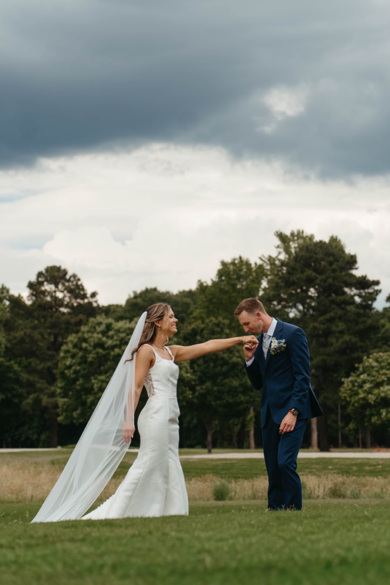 Bride and groom walking hand in hand across a lawn